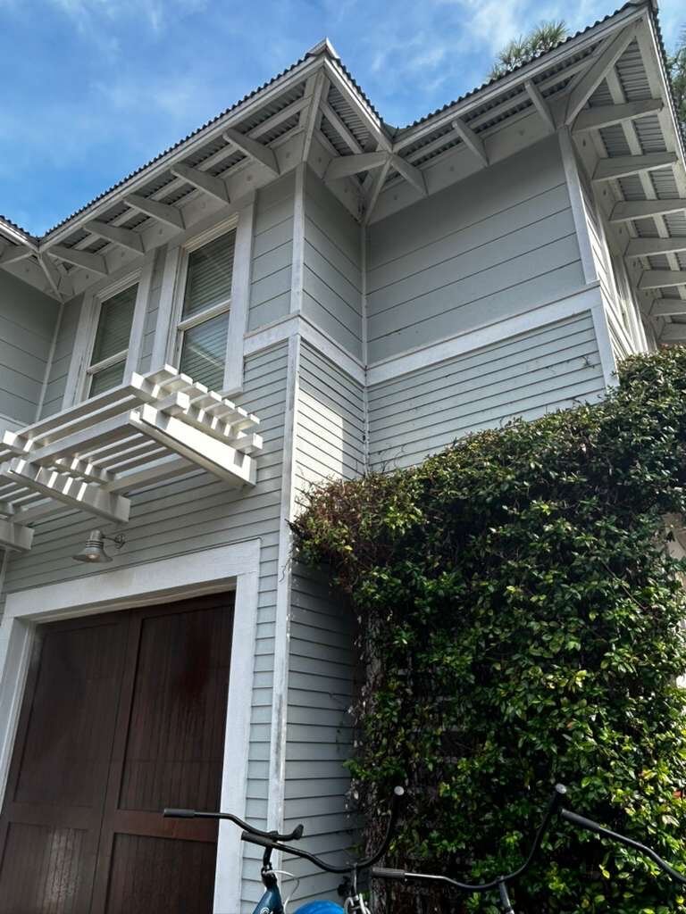 Same gray coastal home after soft washing, siding restored to a bright, clean finish