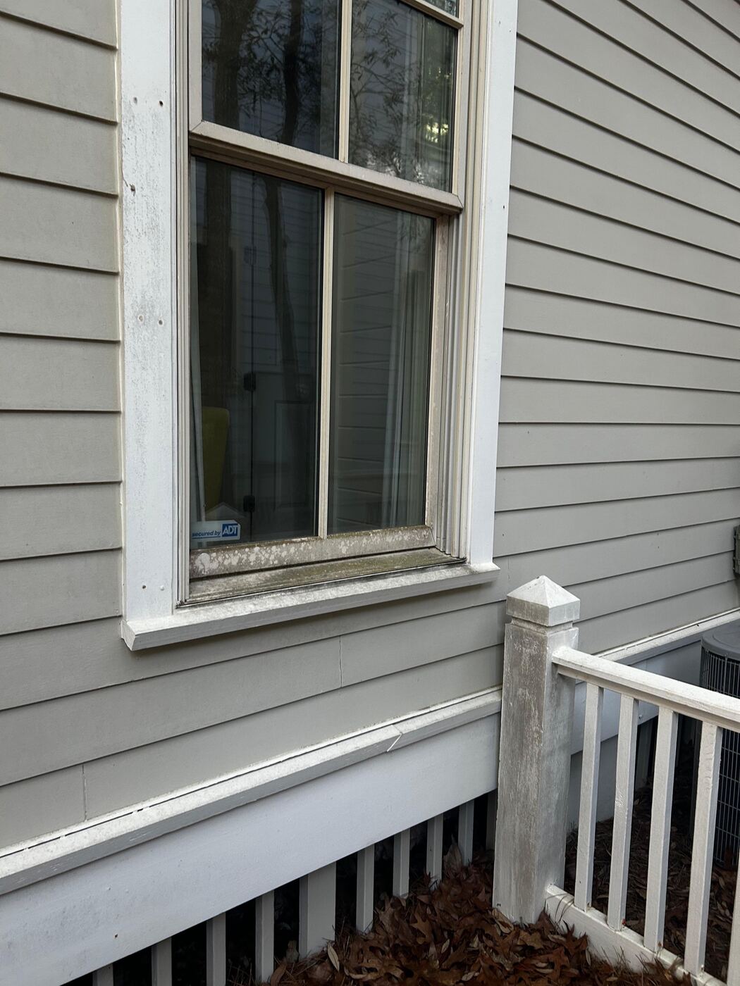 Same window area after cleaning, siding and sill restored to clean white and gray